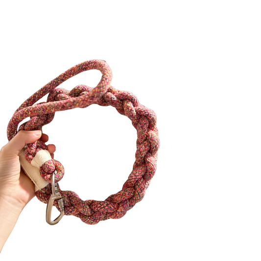 Red Rope dog Leash with a carabiner held by a hand against a white background