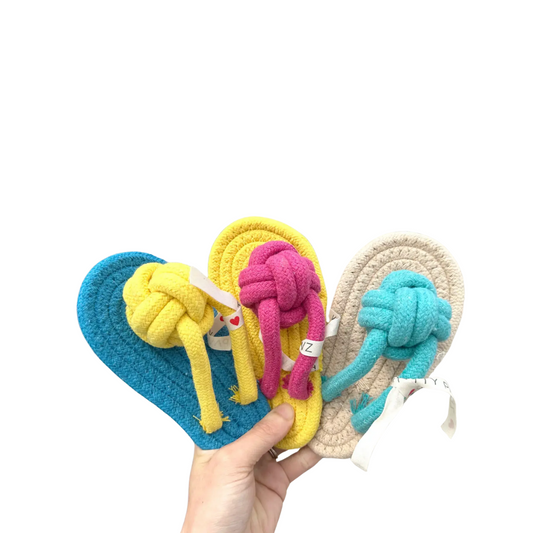 Three colorful knotted slipper rope toys held by a hand on a white background