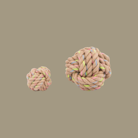 Two knitted rope balls with colorful yarn on a beige background
