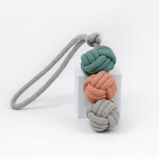 A handcrafted pet tug toy made of cotton rope in shades of green, gray, and pink, designed in the shape of an ice cream.