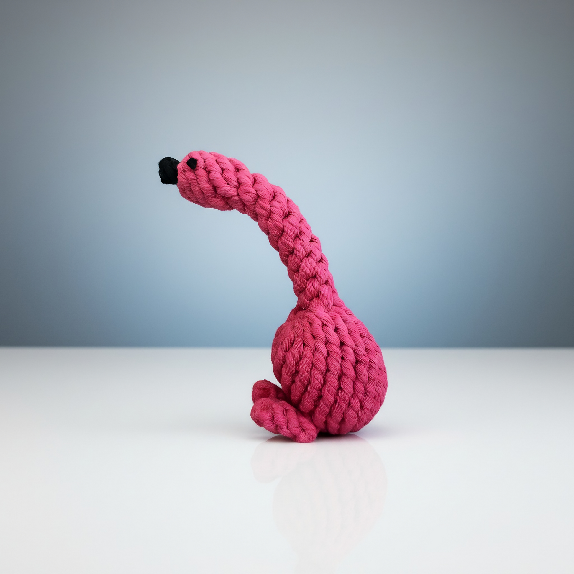 Pink knitted toy resembling a flamingo on a light gray background
