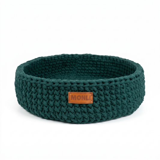 Green knitted pet bed with a brown label on a white background