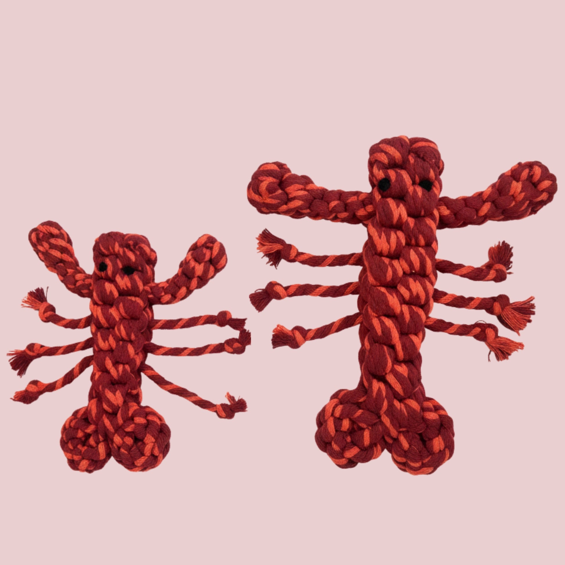 Two red rope toys shaped like lobsters on a pink background