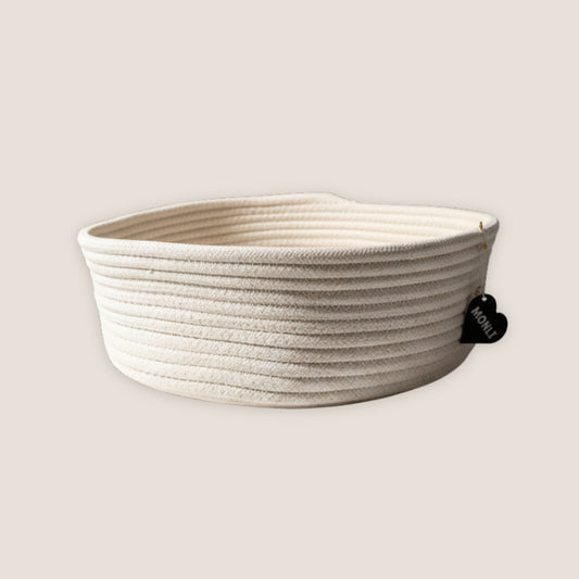 Beige woven basket with a black heart-shaped tag on a light beige background