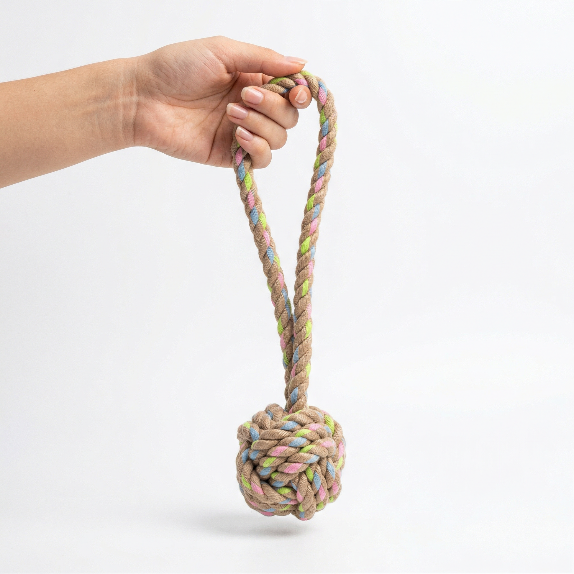 Hand holding a colorful braided hemp and cotton rope toy against a white background