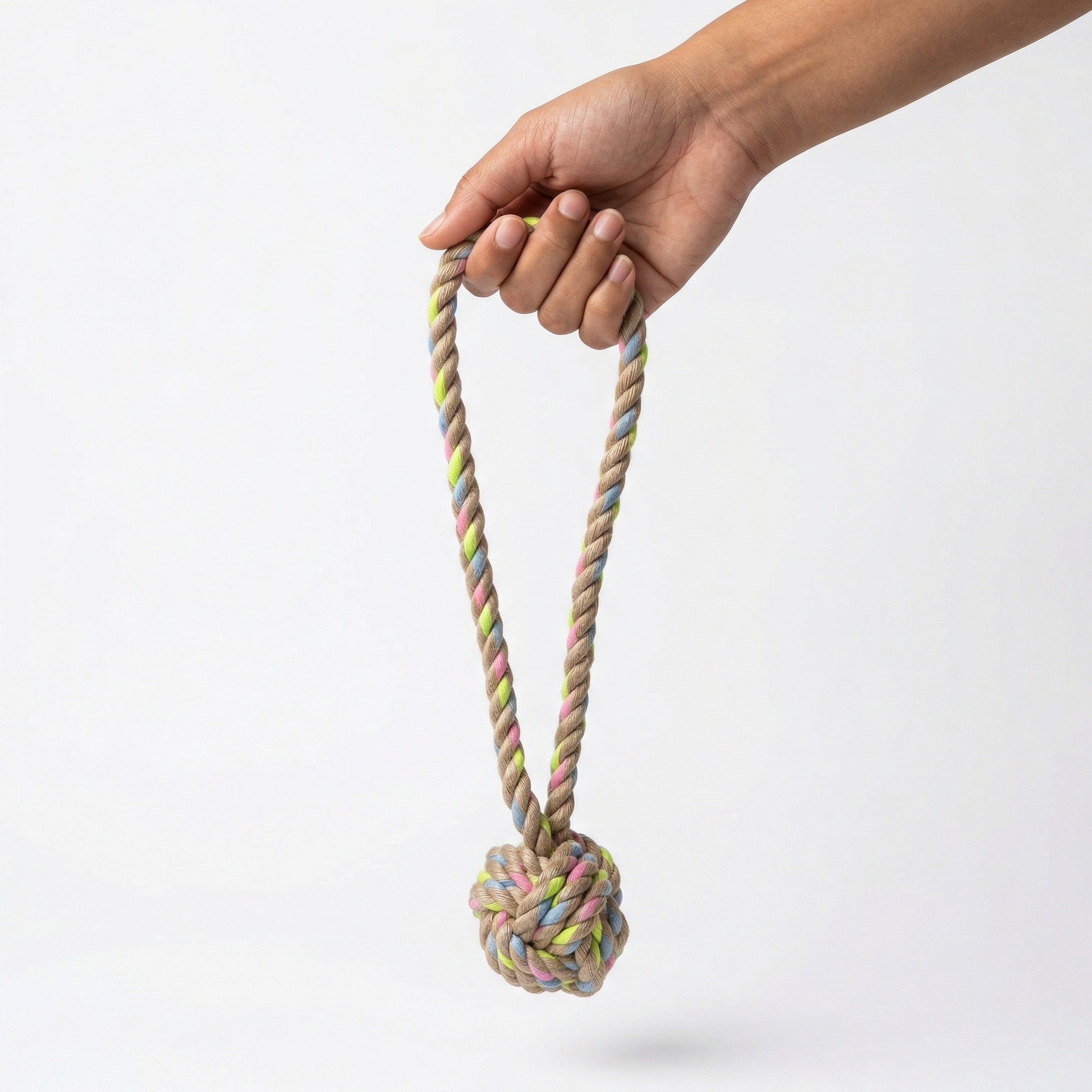 Hand holding a colorful rope toy with a knot on a white background