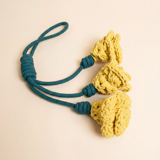 A set of three yellow knotteds daylily flower snuffle dog rope toy with teal cords, arranged on a light beige background.