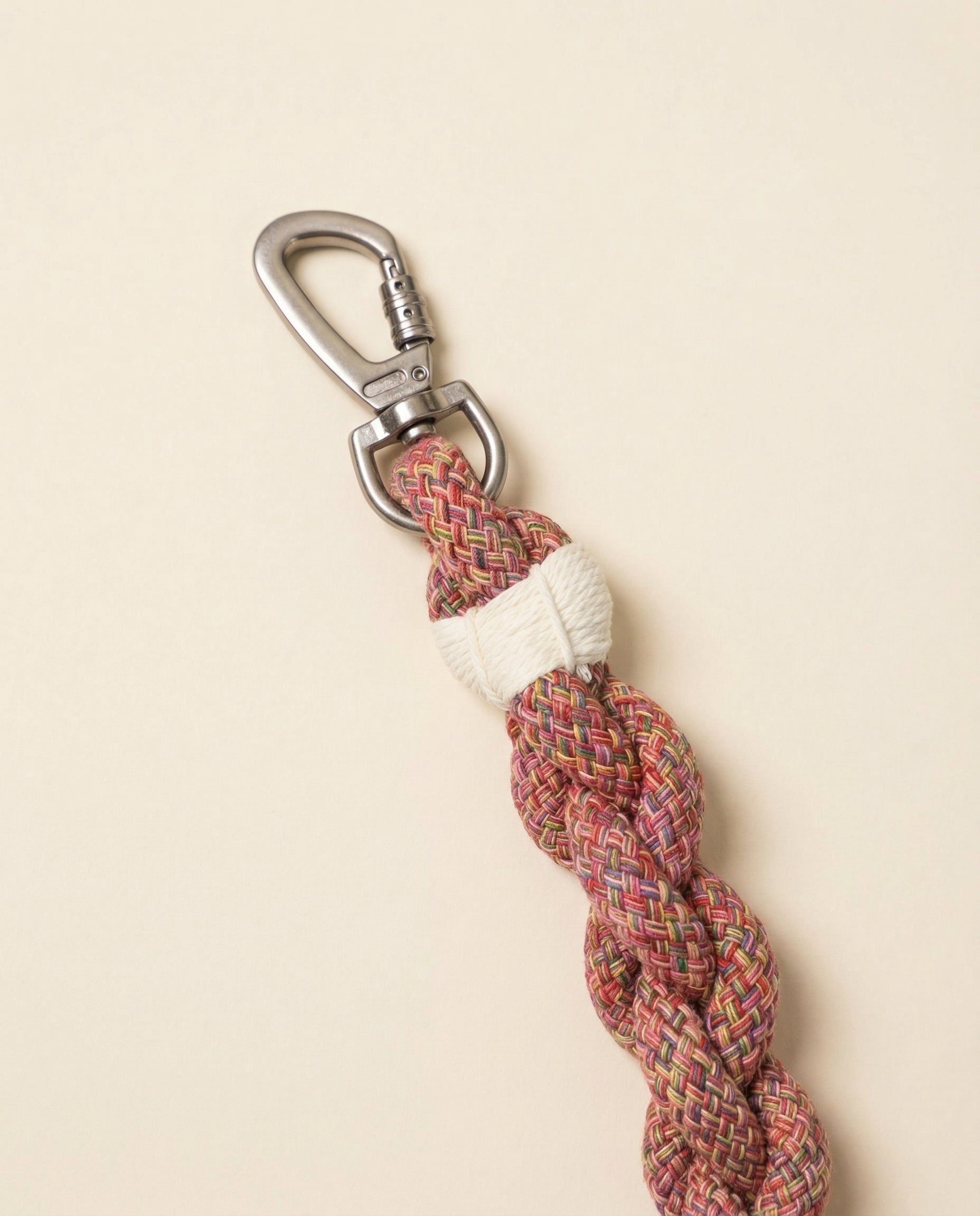 Braided rope keychain with a metal carabiner on a beige background