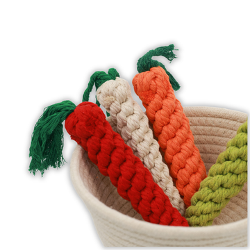 Set of colorful knitted carrot toys with green stems in a woven basket on a white background