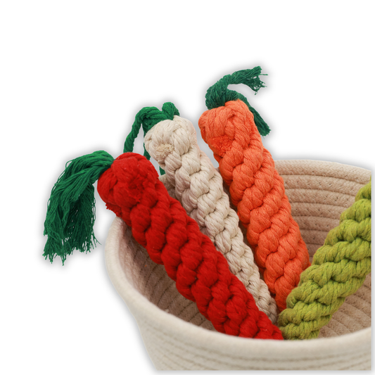 Set of colorful knitted carrot toys with green stems in a woven basket on a white background