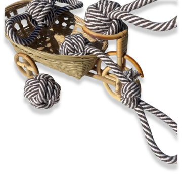 Wicker toy cart with striped rope and a knotted ball on a white background