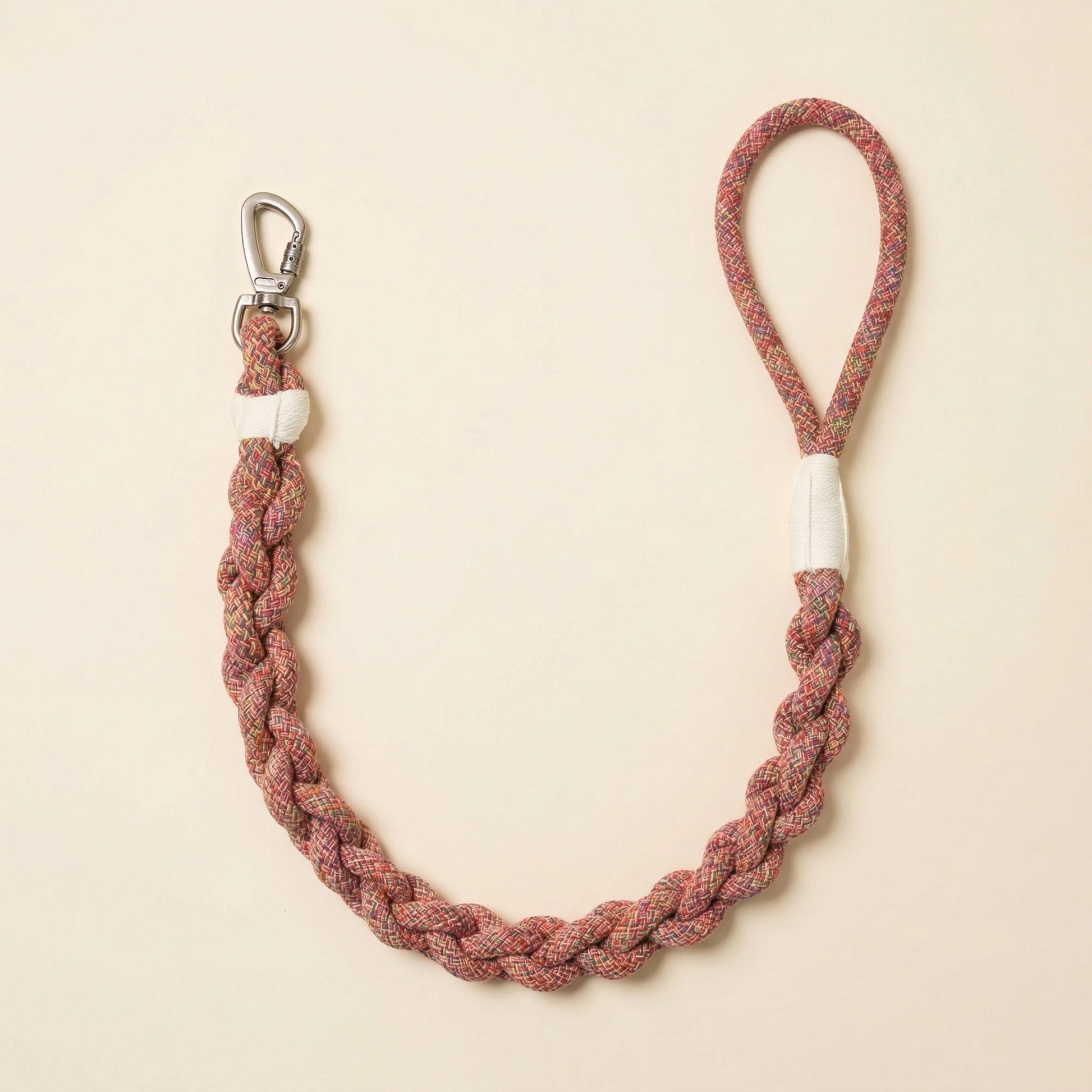 Braided rope dog leash with metal clip on a beige background