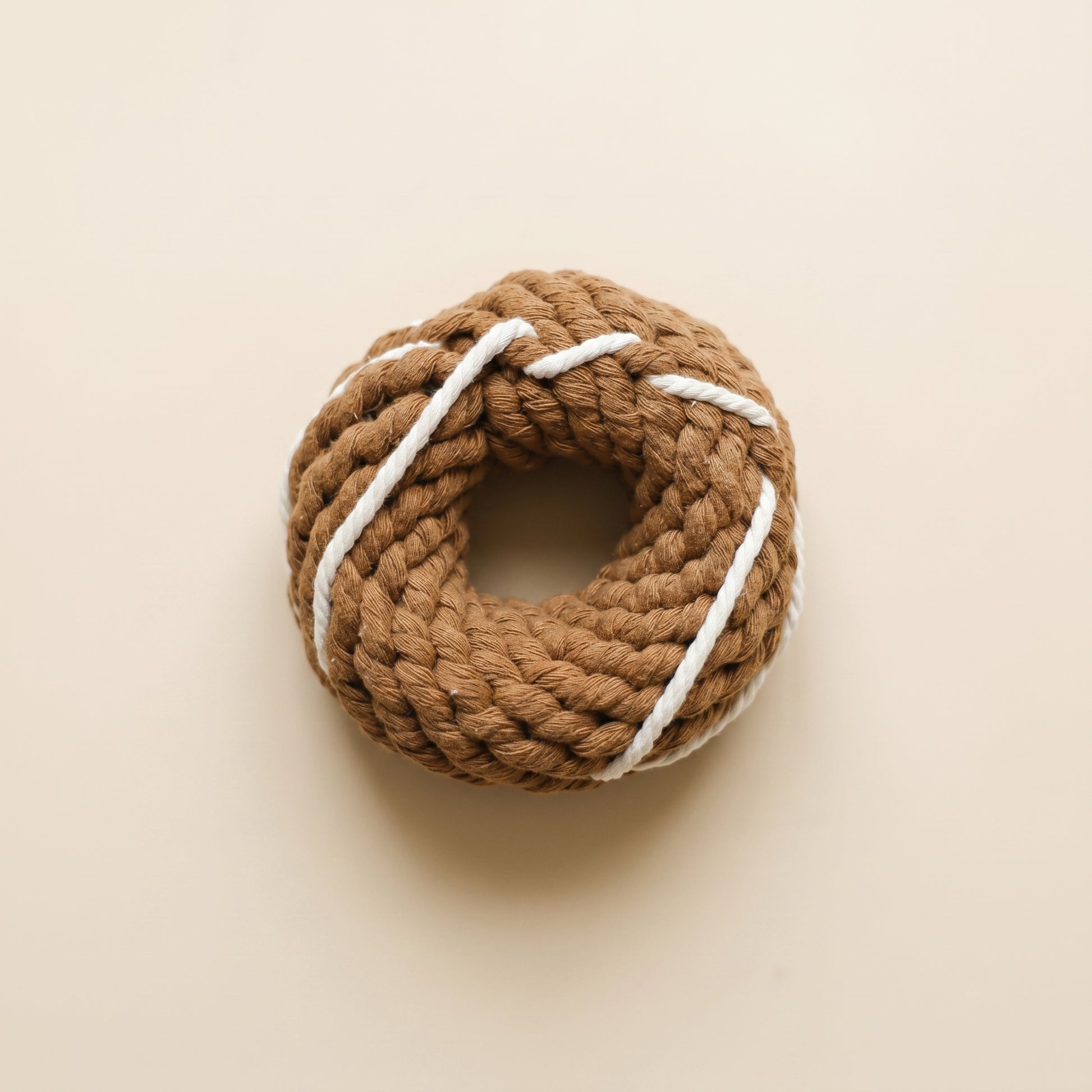 Brown rope donut toy with white string on a beige background