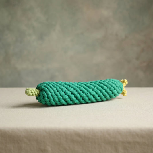 Green cucumber rope toy on a neutral background