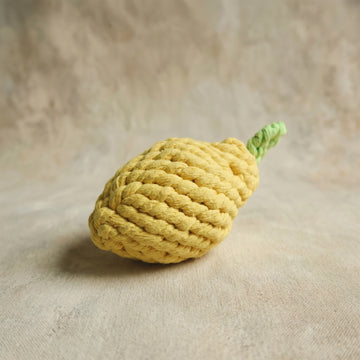 Yellow knitted lemon-shaped toy on a beige surface