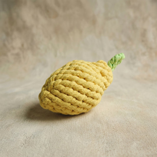 Yellow knitted lemon-shaped toy on a beige surface