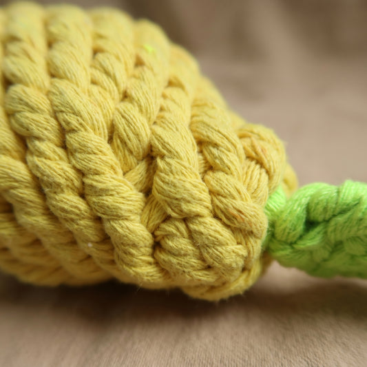 Close-up of a yellow braided rope toy on a wooden surface